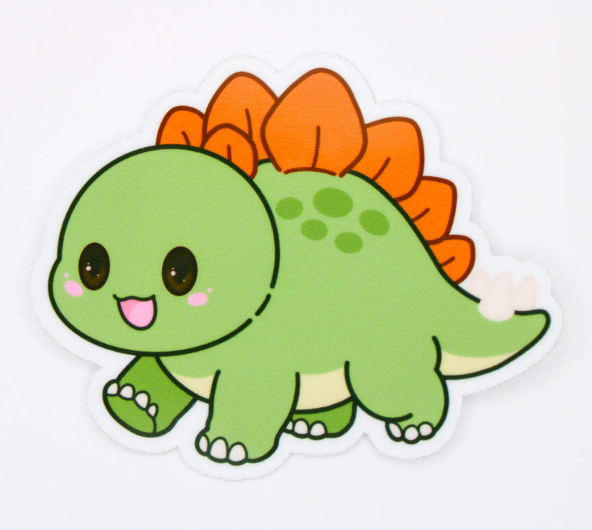 A cute cartoon dinosaur sticker or decal featuring a green kawaii Stegosaurus with orange spikes, large black eyes, and a white outline on a plain white background.