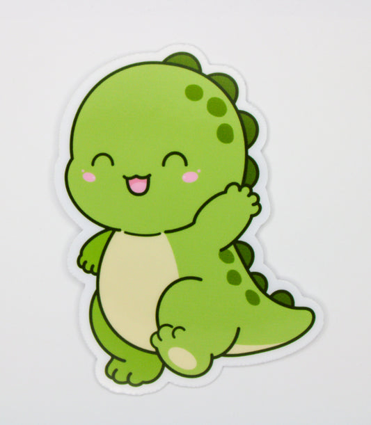 A die-cut sticker featuring a cute, smiling green cartoon dinosaur with a cream belly, shown on a plain light gray background.