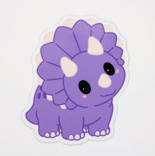 A die-cut vinyl sticker of a cute purple cartoon Triceratops dinosaur, shown on a clean white background.