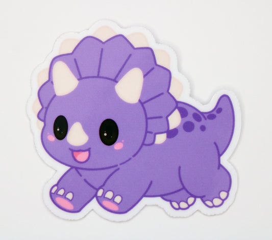 A die-cut vinyl sticker of a cute purple cartoon Triceratops dinosaur, shown on a plain white background.