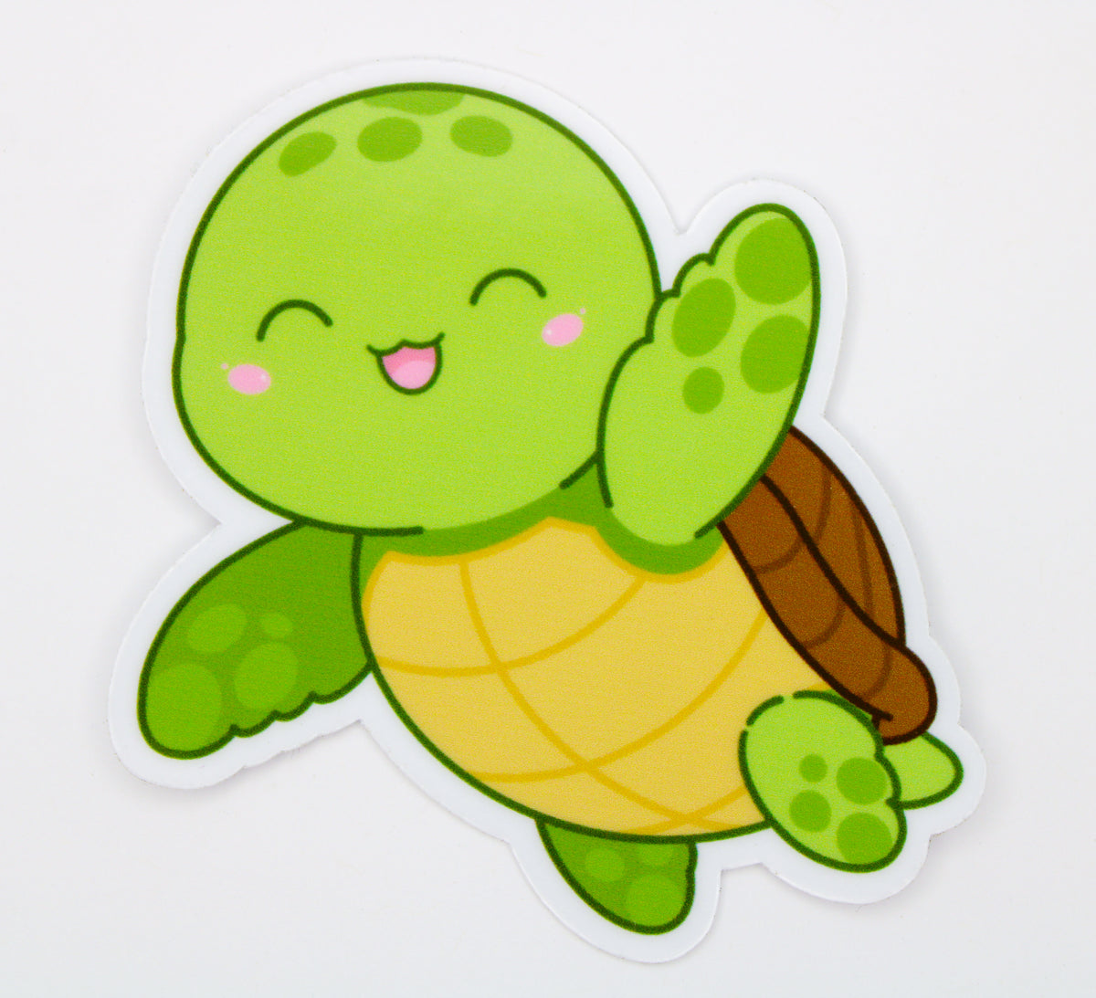 A cute cartoon sea turtle sticker with a green head and flippers, a yellow shell, and a brown shell, waving on a white background.