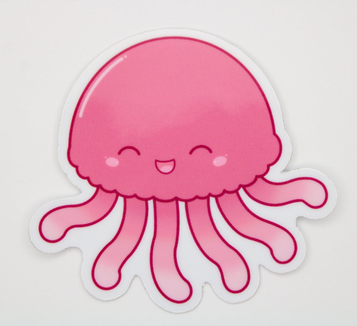 A cute pink jellyfish sticker with a smiling face and wavy tentacles, shown on a plain white background.
