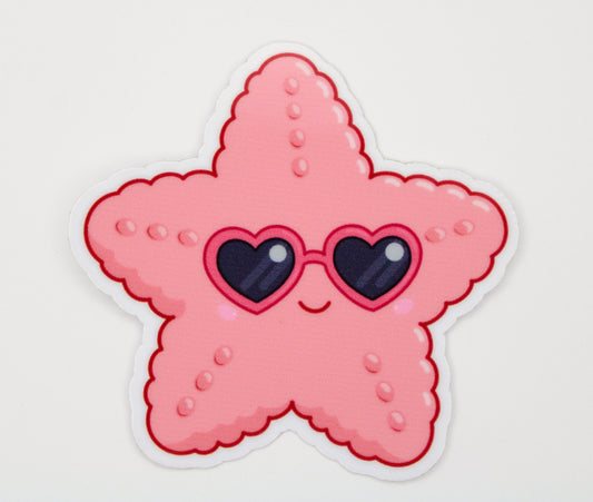 A die-cut sticker featuring a cute pink starfish character wearing heart-shaped sunglasses, shown on a plain white background.
