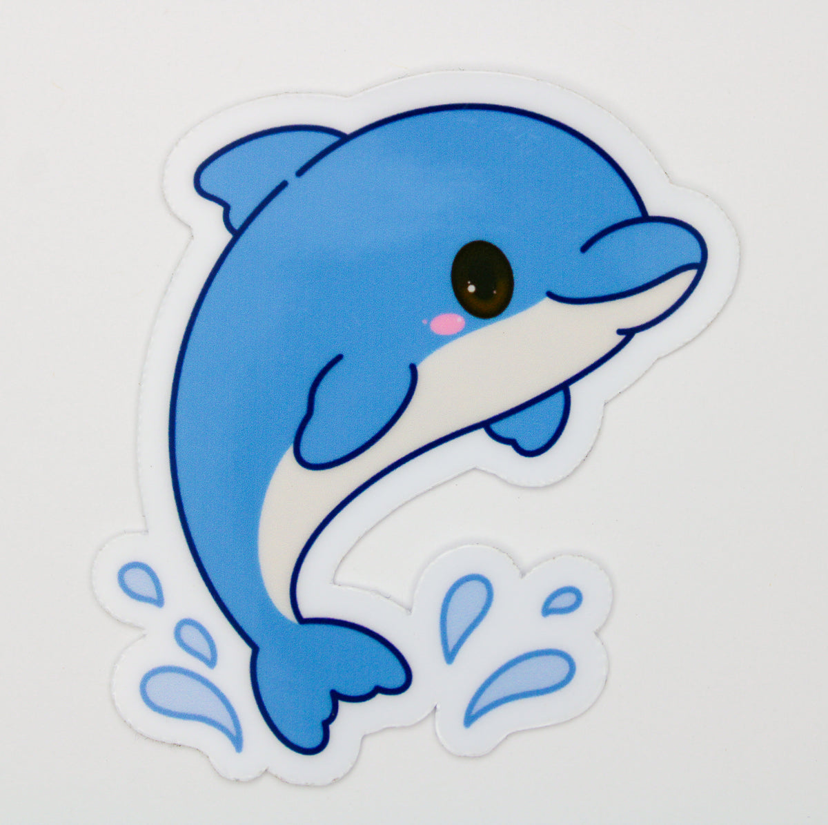 A die-cut vinyl sticker featuring a cute cartoon blue dolphin jumping up with water splashes, shown on a plain white background.